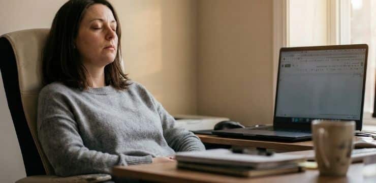 Reclaim Your Elite Focus productivity quotes for focus, female creator closing eyes at desk during afternoon cognitive reset